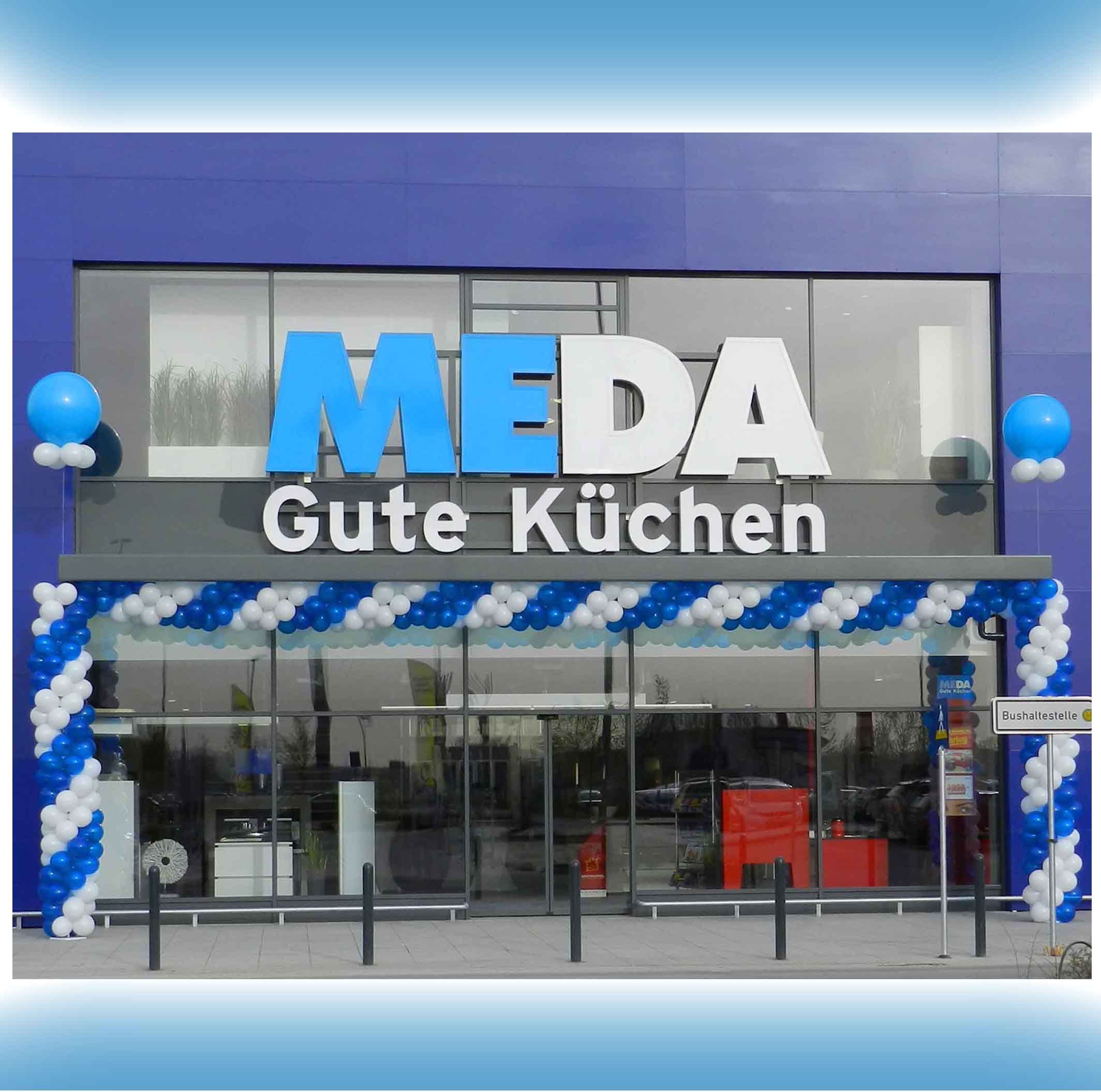 Beeindruckender Torbogen aus blauen und weißen Ballongirlanden zur Eröffnung von MEDA Küchen in Würzburg, schmückt den Eingangsbereich.
