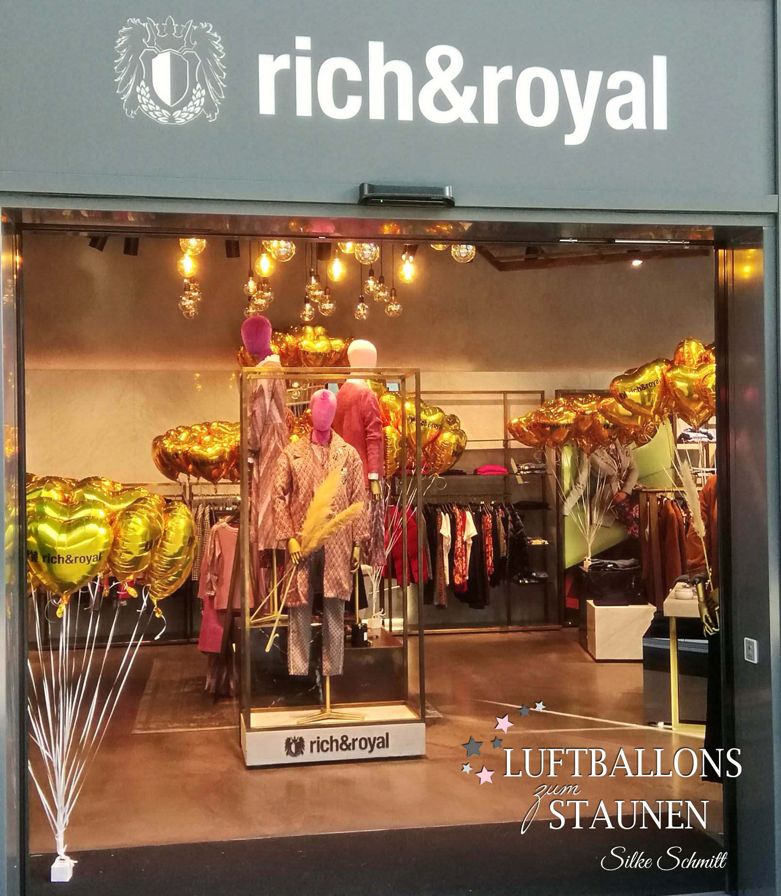 Die geöffneten Eingangstüren gewähren einen Blick auf den stilvollen Store von Rich & Royal. Die Mode ist umringt von zahllosen goldenen Logo-Herzen.
